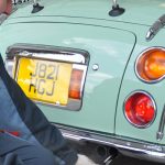 someone attending to the rear of a Nissan Figaro
