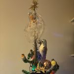 the top of a Christmas tree with various ornaments including a fairy on the top