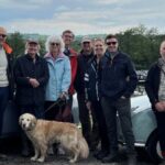 Members stood smiling by two Figaros